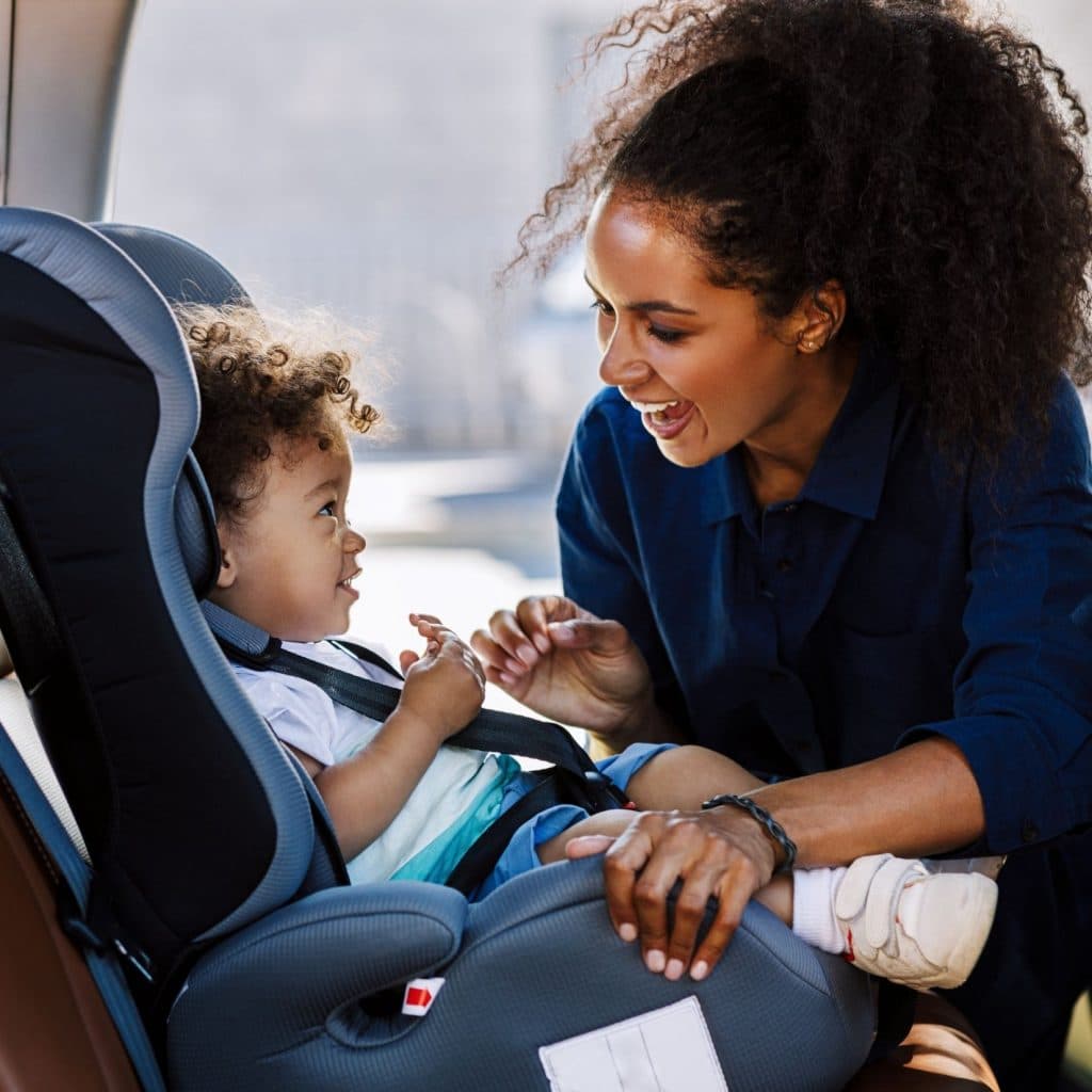 mom putting baby in car seat